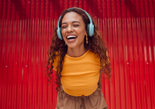 Urban, joy and woman with headphone music enjoying happy rhythm with bluetooth connection. Smile of latino girl listening to feel good streaming audio while resting at wall for leisure break.