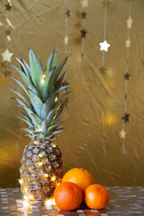 New Year's table, pineapple and oranges against the background of golden stars