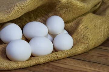 White chicken eggs close-up on a background of burlap, rustic still life. Concept and idea for homemade organic food artwork. environmentally friendly products. Farm products