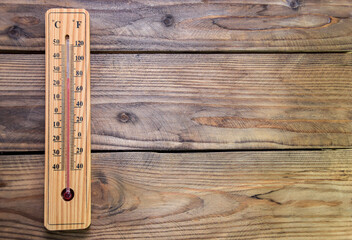 On a wooden wall hangs a wooden mercury thermometer at around 25 with a scale from minus 40 to plus 50 degrees near zero. Air temperature in the room. 25 degrees Celsius or 80 degrees Fahrenheit. - obrazy, fototapety, plakaty