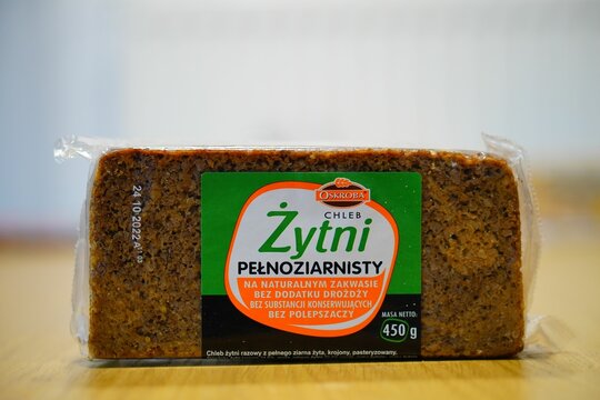 Closeup shot of Polish Oskroba dark full grain bread on a wooden table with blur background