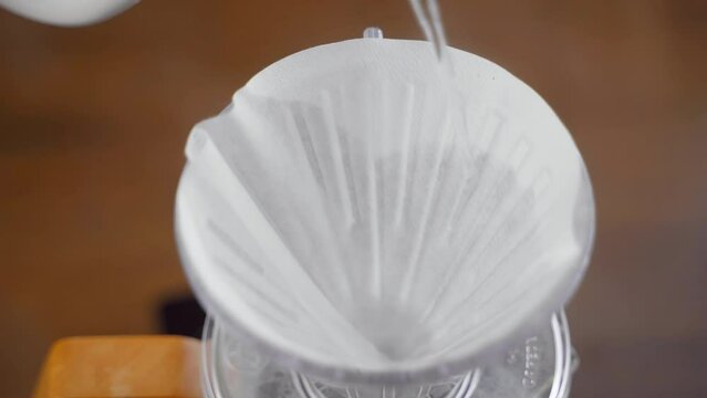 Closeup view of barista preheating coffee paper filter