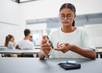 Diabetes, finger prick and black woman with blood sugar test to check glucose level sitting at desk...