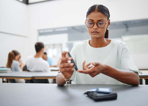 Diabetes, Finger Prick And Black Woman With Blood Sugar Test To Check Glucose Level Sitting At Desk In Class. Sick And Diabetic Female Student Using Glucometer Pen For Control And Healthcare