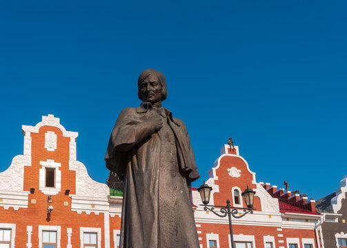 Yoshkar-Ola, Russia - August 25, 2022: Statue of Nikolai Vasilievich Gogol against the backdrop of the beautiful buildings of the Amsterdam embankment.