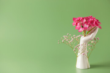 Creative art concept plaster hand holder fresh flowers gypsophila and hydrangea on green background. Copy space