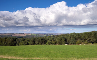 Obraz premium The dramatic cloud layer of a storm, thunderstorm building over the green fields and forests of the English countryside.