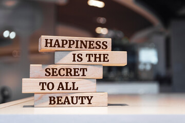 Wooden blocks with words 'Happiness is the secret to all beauty'.