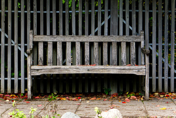 A park bench made of wood in front of wooden fence