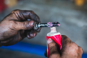 Auto mechanic applying silicone brake grease on brake caliper slide pins.
