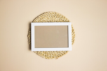 White wooden frame over the natural placemat on brown background. 