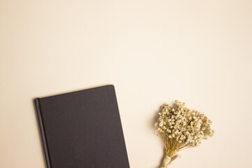 Flower with notebook on brown background with copy space.