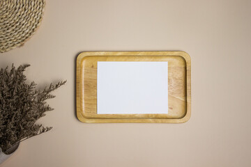 White paper on wooden plate with flowers over the brown background. 
