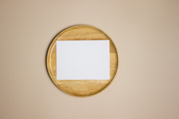 A blank white paper on wooden plate on brown table. 