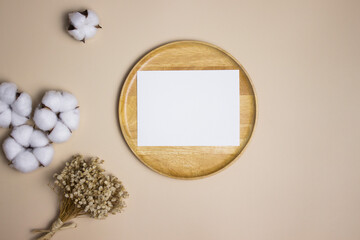 White card and cotton flowers and flower bouquet on brown background. 