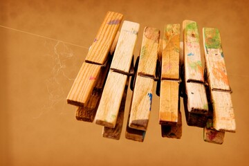 Closeup of row of bamboo clothespins with paint stains hanging on nylon thread against orange wall