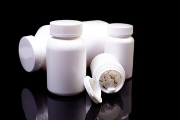 Medical pills in white jar on an isolated black background with reflection