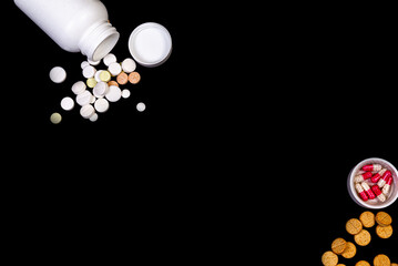 Medical pills flow from a white jar on an isolated black background with reflection a thermometer