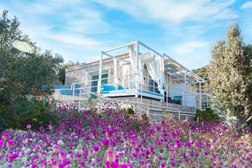 villa by the sea in a green bay with sunbeds, beds and curtains