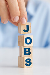 Businesswoman placing wooden blocks on the white table, "Jobs" concept.