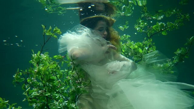 fabulous fairy is swimming in surreal subaquatic garden, fairytale and fantasy dream, young woman in depth