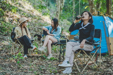 Young women sitting and drink beverage  front of camping tent