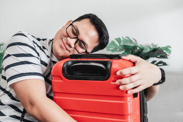 Happy Asian traveler man glasses hugging luggage