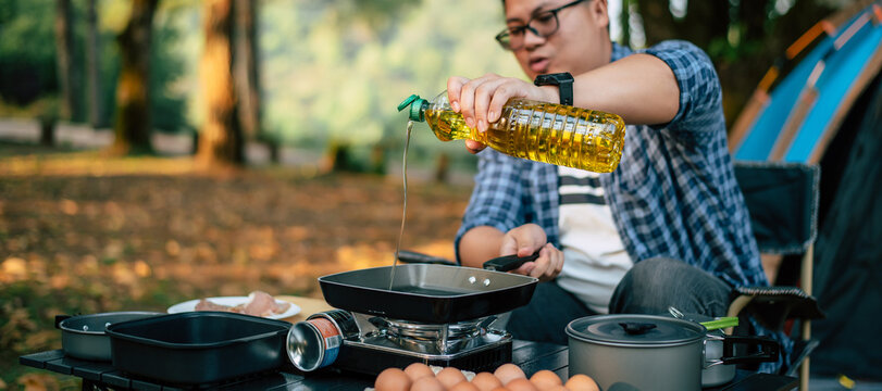 Portrait Of Asian Traveler Man Glasses Pouring Sunflower Oil Into A Frying Pan