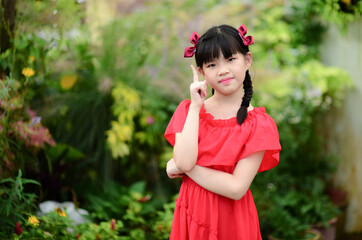 Young pretty girl holding finger up having idea and posing in nice garden