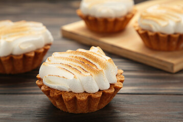 Appetizing lemon cupcakes with white cream on wooden board on brown background. Holiday, surprise, birthday, Valentine's Day.