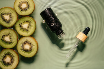 Facial pipette serum black bottle, whey beauty product near fruit kiwi slice in water splashing fresh transparent, fleck