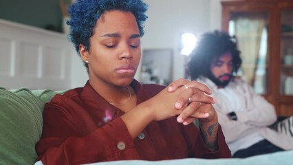Young distressed African American woman cries after quarrel with boyfriend or betrayal gets upset wiping tears from eyes thinks about what to do next sits on sofa in living room. Family problems
