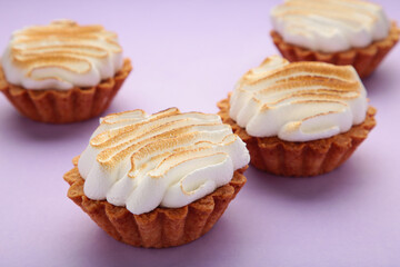 Appetizing lemon cupcakes with white cream on purple background. Holiday, surprise, birthday, Valentine's Day.