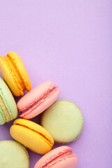 Macarons on purple background. Sweet dessert. Vertical photo