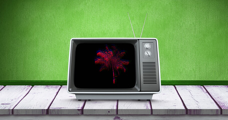 Composite of palm tree in television set over wooden table against green background, copy space