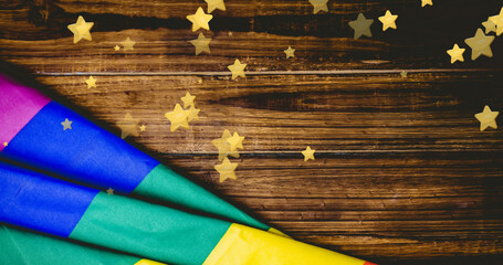 Composite of stars and rainbow flag over wooden table, copy space