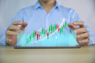businessman using a tablet to plan a strategy that shows a positive digital technology graph chart. The concept is growing stocks