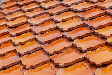 Orange clay tiles overlapping each other on the roof. Geometric pattern from old tile. Selective focus. Shallow DOF. Horizontal.
