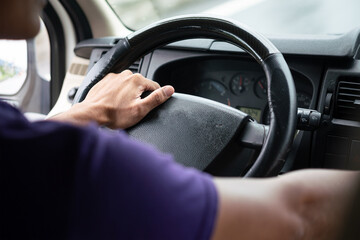 Action of a driver hand is holding and controlling on car's steering wheel during driving, photo from behind. Transportation occupation service with people part, selective focus.