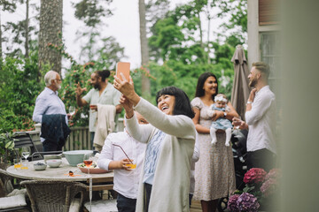 Grandmother taking selfie with grandchild at dinner party