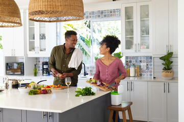 Happy african american couple cooking dinner together in kitchen