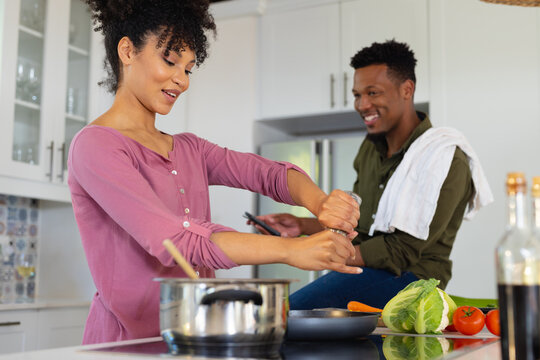 Happy african american couple cooking dinner together in kitchen