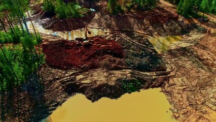 Aerial drone backward moving shot of deforested areas affecting the flow of river and JCB leveling land for development purposes at daytime.