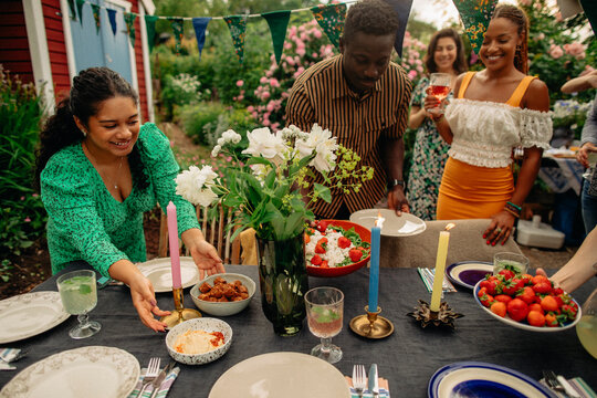 Male And Female Friends Setting Up Table During Garden Party