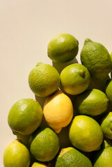 Overhead view of tight arrangement of yellow and green lemon fruit on gray background with hard shadows. Top view, flat lay. Green living and eco-friendly products