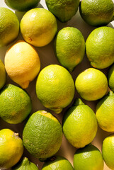 Overhead view of tight arrangement of yellow and green lemon fruit on gray background with hard shadows. Green living and eco-friendly products