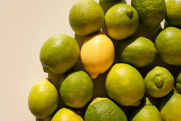 Overhead view of tight arrangement of yellow and green lemon fruit on gray background with hard shadows. Top view, flat lay. Green living and eco-friendly products