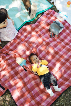 Directly above shot of baby girl lying on checked picnic blanket