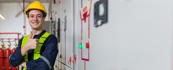 Electrical engineer wear helmet and show thump up near Power Distribution Cabinet in the control...