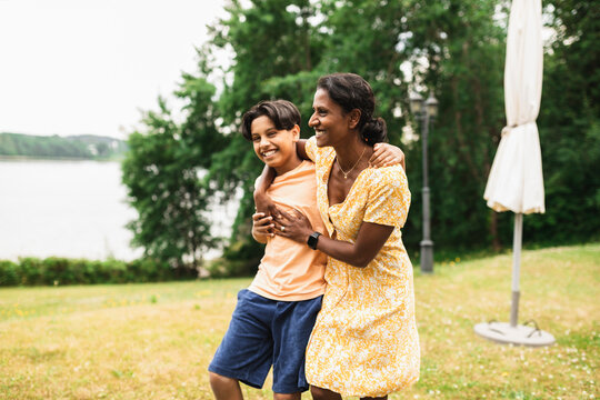 Happy Woman With Arm Around Son Enjoying In Back Yard